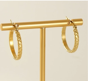 Detailed close-up of 18K gold-plated twisted hoop earrings on a T-bar display stand