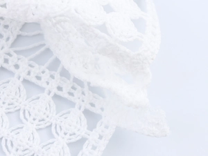 Detailed macro shot of white floral lace crochet texture on elegant polo shirt sleeve