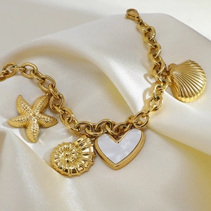 Detail of 18K gold plated bracelet featuring starfish, seashell and heart pendants