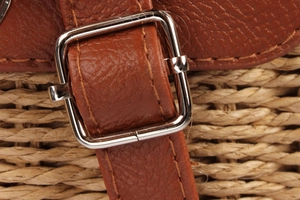 Detailed close-up of brown litchi leather strap, silver buckle and woven paper straw texture