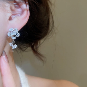 Gros plan d'une boucle d'oreille rose en zircons sur mannequin avec détail de feuille