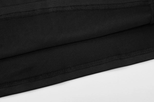 Detail shot of black knitted fabric with pleated hem and precise stitching on the dress