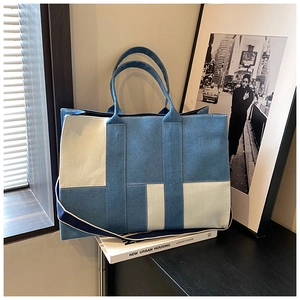 Close-up of contrast denim patchwork tote bag with adjustable strap on wooden surface