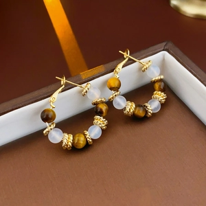 Detailed shot of gold-plated hoop earrings with tiger eye and white translucent beads