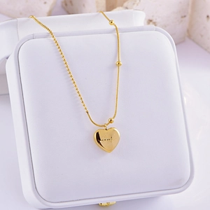 Detail of golden heart pendant with Lucky engraving on a dual pearl and snake chain