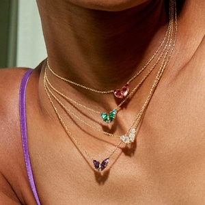 Close-up of four-color butterfly necklaces with gemstone pendants on a golden chain