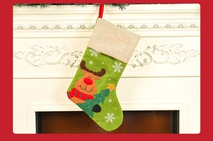Close-up of green linen Christmas stocking with reindeer embroidery hanging on a fireplace