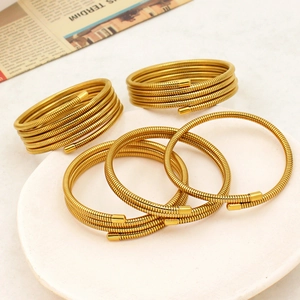 Golden spiral spring bracelet set in stainless steel displayed on a ceramic plate