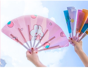 Close-up of colorful cartoon folding fans for kids against a clear blue sky