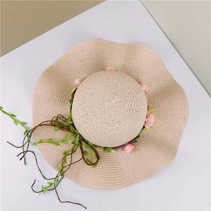 Detail of summer straw sun hat featuring pink rose floral trim and wavy wide brim design