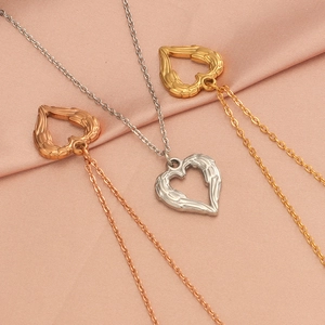 Detailed view of angel wing heart necklaces in gold, silver, and rose gold on pink silk