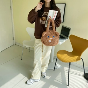 Detail of cute brown plush teddy bear handbag with cartoon embroidery in a lifestyle setting