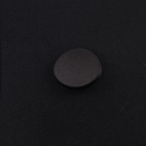 Close-up of black fabric-covered button on sleeveless commuter halter top vest