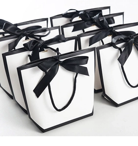 Detailed view of white gift bags with black trim and elegant ribbon bow tie