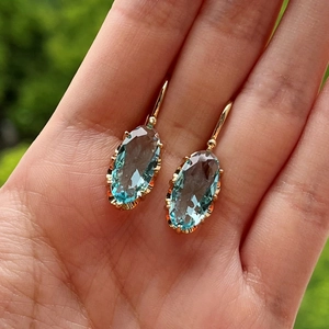 Detalle de pendientes de piedras ovales azul claro con ganchos dorados franceses