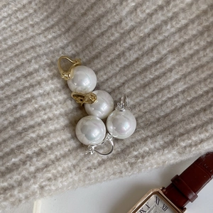 Detail of elegant gold and silver pearl earrings displayed on a soft textured sweater