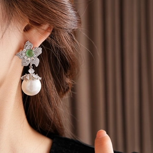 Gros plan de boucles d'oreilles vintage fleur avec gemme verte et grande perle blanche