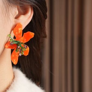 Close-up of vintage flower earrings with orange petals and green beads on model