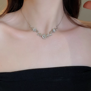 Detailed close-up of a silver floral necklace with zircon crystals on a model neck