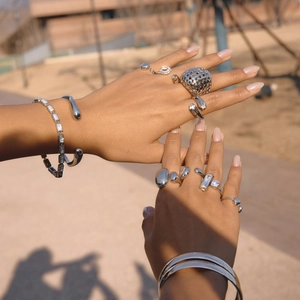 Detail of silver hollow mesh sphere ring and stacked zircon bracelets on hands