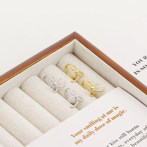 Detailed macro of gold and silver bow-knot twisted rope hoop earrings in jewelry box