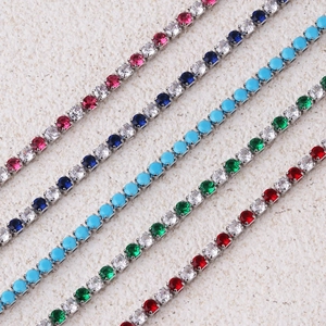 Detail of colorful tennis chains featuring turquoise, blue, and red zircons in silver claws