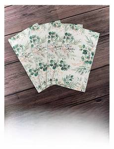 Close-up of rectangle paper napkins with green tropical leaf patterns on a dark wood background