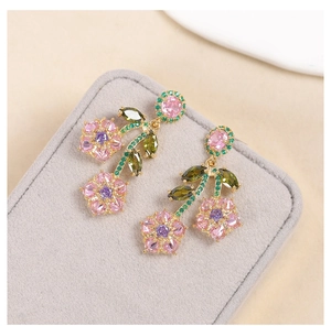 Close-up of pink zircon flower earrings with green leaf stones in a velvet box