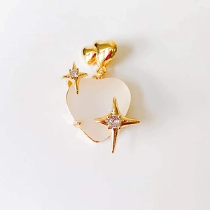 Detail view of 18k gold heart pendant with white center and sparkling star accents