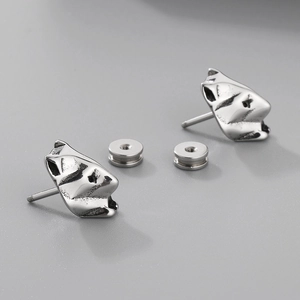 Detailed view of silver wolf head stud earrings with vintage embossed metal texture