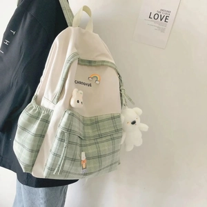 Detail of grid-pattern school backpack with plush bear charm and cute embroidery