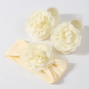 Détail de chaussettes et bandeau bébé en tricot crème avec fleurs en tissu souple