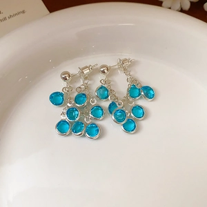 Detailed close-up of blue gemstone tassel earrings resting on white ceramic tray