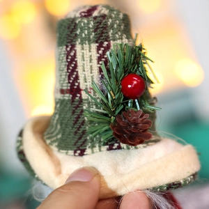 Dettaglio di un mini cappello di Natale a quadri con pigne piccole e bacche rosse