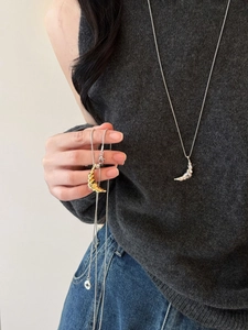 Detail of twisted crescent moon pendant necklace in gold and silver plating on model