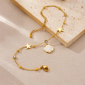 Gold starfish anklet with natural stones and iridescent shell pendant on stone surface