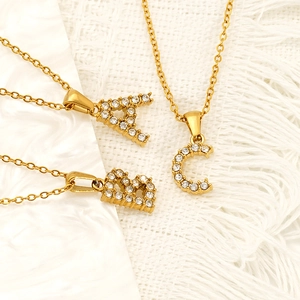 Gold square initial necklace with zircon letters A B C on elegant marble background