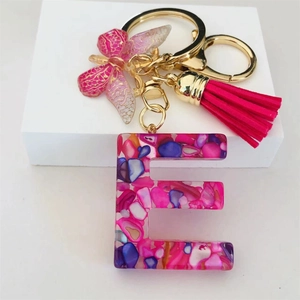 Detail of Letter E resin keychain with pink stones, butterfly charm and pink tassel