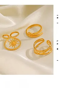 Detailed view of vintage gold plated snake and sunburst rings on white satin fabric