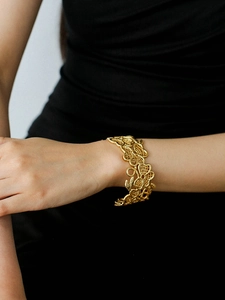 Detailed macro view of 18k gold plated hollow lace flower bangle on female wrist
