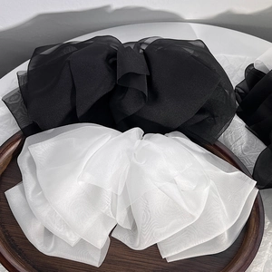 Detail view of large multi-layer chiffon bow hair clips in black and white colors