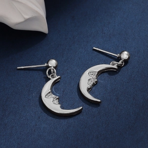 Retro crescent moon earrings with engraved face detail on textured dark background