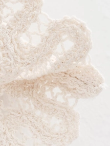 Vue macro du tissu en dentelle crochetée beige montrant les textures et motifs de tricot