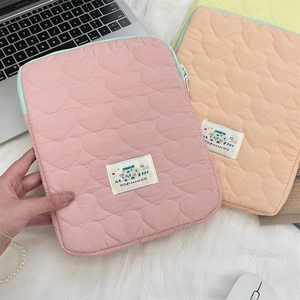 Detailed close-up of quilted heart-pattern laptop sleeves in pink and yellow fabric