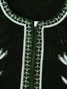 Close-up of silver sequin embroidery and geometric patterns on dark green velvet vest