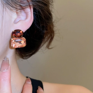 Detail of luxury geometric earrings featuring red oval and pink rectangular gemstones