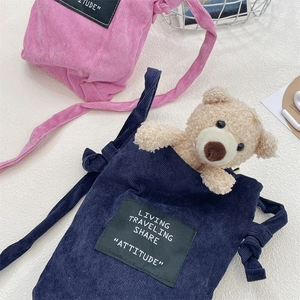 Detail of pink and navy corduroy crossbody bags with a cute teddy bear plush insert