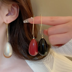 Détail de boucles d'oreilles perles en forme de goutte en blanc, rouge et noir avec crochets