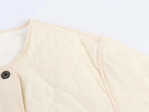 Close-up of cream quilted jacket featuring high-quality stitching and black button detail