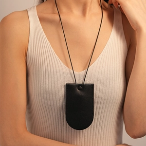 Close-up of black leather key pouch necklace with metallic snap button on white vest